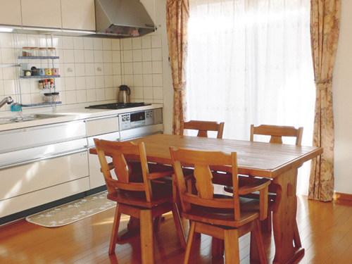 ダイ二ングセットがゆったりと置ける、広さ十分のDK。奥は大容量の収納を備えたシステムキッチン